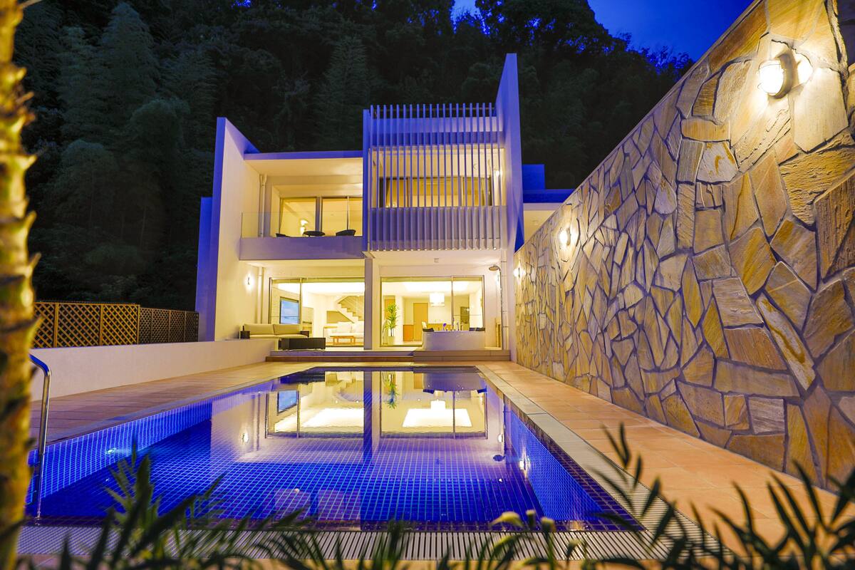 A modern two-story house with a swimming pool in front.
