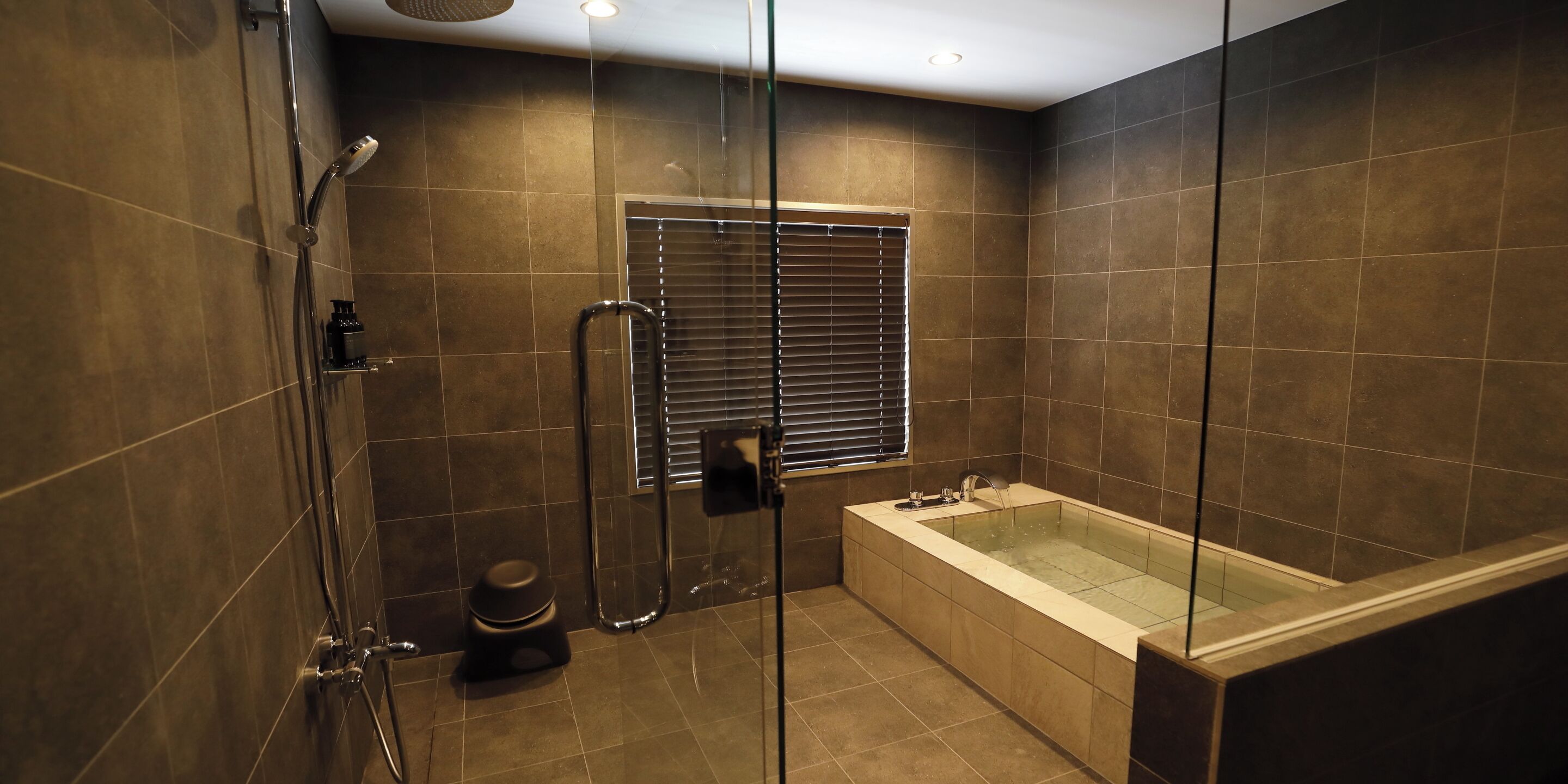 A modern bathroom with a glass-enclosed shower, a standalone toilet, and a freestanding bathtub.