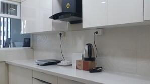 Une cuisine avec des armoires blanches, une hotte noire et une machine à café posée sur le plan de travail.