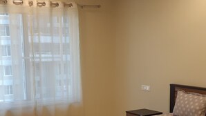 Une chambre à coucher avec un lit, une table de chevet, un ventilateur de plafond et une fenêtre avec des rideaux.