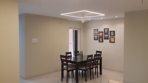 Un coin repas comprenant une table rectangulaire et six chaises, un luminaire au plafond et des affiches motivantes accrochées au mur.