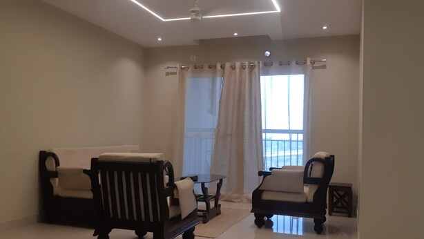 Un salon avec deux canapés, une petite table et un luminaire suspendu au plafond.
