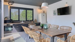 A modern kitchen with a dining area, featuring a large window, built-in appliances, and wicker chairs. - Awesome home in Sveti Petar u Sumi (Sveti Petar u Sumi)