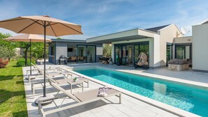 A modern outdoor pool area with lounge chairs, a barbecue, and a covered seating area. - Awesome home in Sveti Petar u Sumi (Sveti Petar u Sumi)