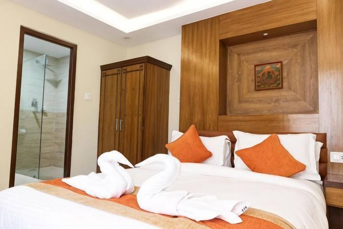 A hotel room with a bed, wooden wardrobe, and a shower area.