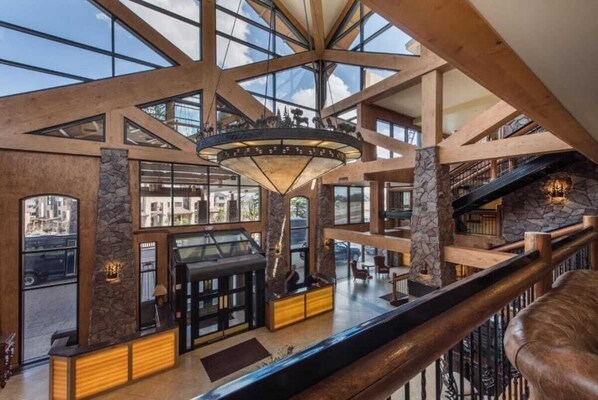 A spacious lobby with a high ceiling, large windows, and a central chandelier.