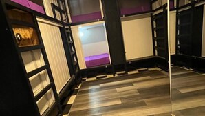 Ein Zimmer mit Holzboden, schwarz-weißen Regalelementen und einer lilafarbenen Akzentwand.