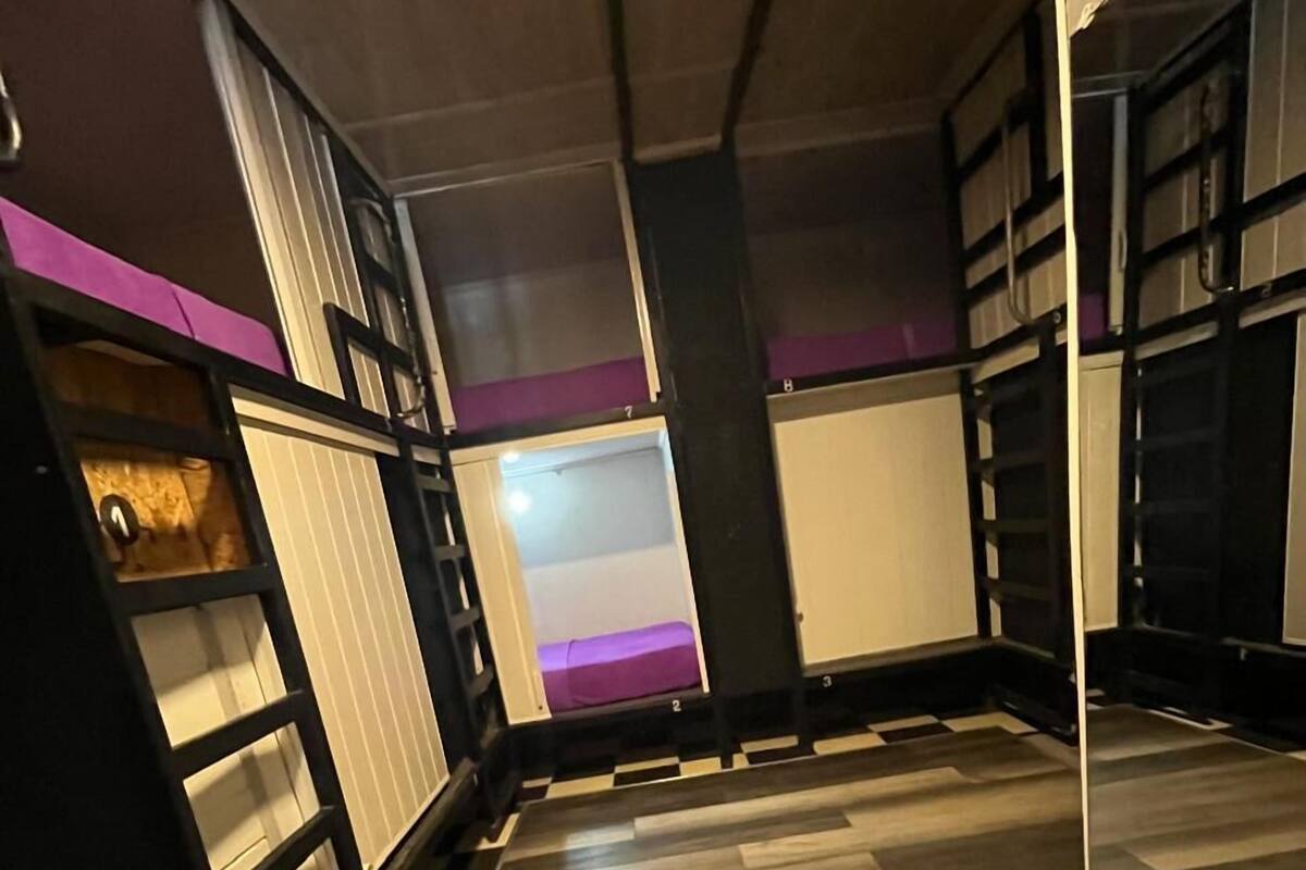 Ein Zimmer mit Holzboden, schwarz-weißen Regalelementen und einer lilafarbenen Akzentwand.