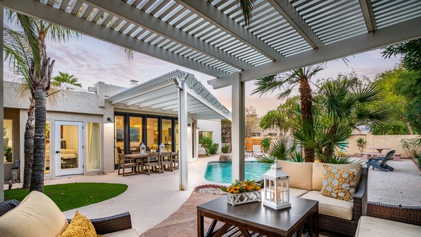 Una veranda esterna coperta con piscina, zone relax e un pergolato.