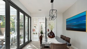 Un'area pranzo moderna con una porta vetrata che dà su un patio, un quadro di grandi dimensioni appeso alla parete e un tavolo centrale con sedie.
