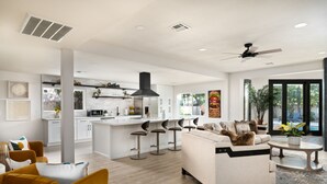 Un'ampia zona giorno moderna, open space, con angolo cucina, divano e bancone bar.