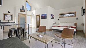 A modern, open-plan living space with a kitchen, dining area, and bedroom. - CAMP RANDONNEE__CABIN 4 (Mosier)