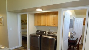 A laundry room with stainless steel washers and dryers, wooden cabinets, and a dining area with a table and chairs. - Great conveniently located home. Near mall and many restaurants.  (Tucson)