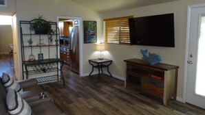A living room with a sofa, a coffee table, a TV, and a kitchen in the background. - Great conveniently located home. Near mall and many restaurants.  (Tucson)