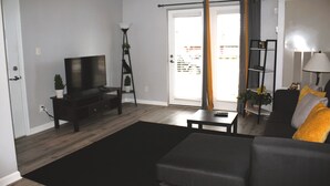 A living room with a sofa, a TV, a coffee table, and a bookshelf. - King Bed. Funny Bone, Fraze, WPAFB, museum Adventure Reef. Fun get away!  (Kettering)
