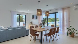 Un salon moderne comprenant un canapé, une table à manger, des chaises et donnant sur une piscine.