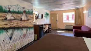 Una habitación con un mural de paisaje desértico, un escritorio con una silla, un sofá y una puerta.