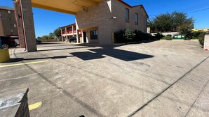 Una estación de servicio con estacionamiento de concreto, un edificio de techo rojo y un cielo azul despejado.