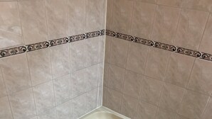 Una bañera de hidromasaje en esquina con asientos integrados y un panel de control.