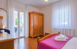 A hotel room with a bed, a wooden wardrobe, a desk, and a view of the outdoors through a glass door. - Stunning apartment in Labin - Rabac (Labin - Rabac)