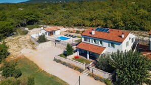 Une villa dotée d’une piscine, de panneaux solaires et d’un chemin en pierre.