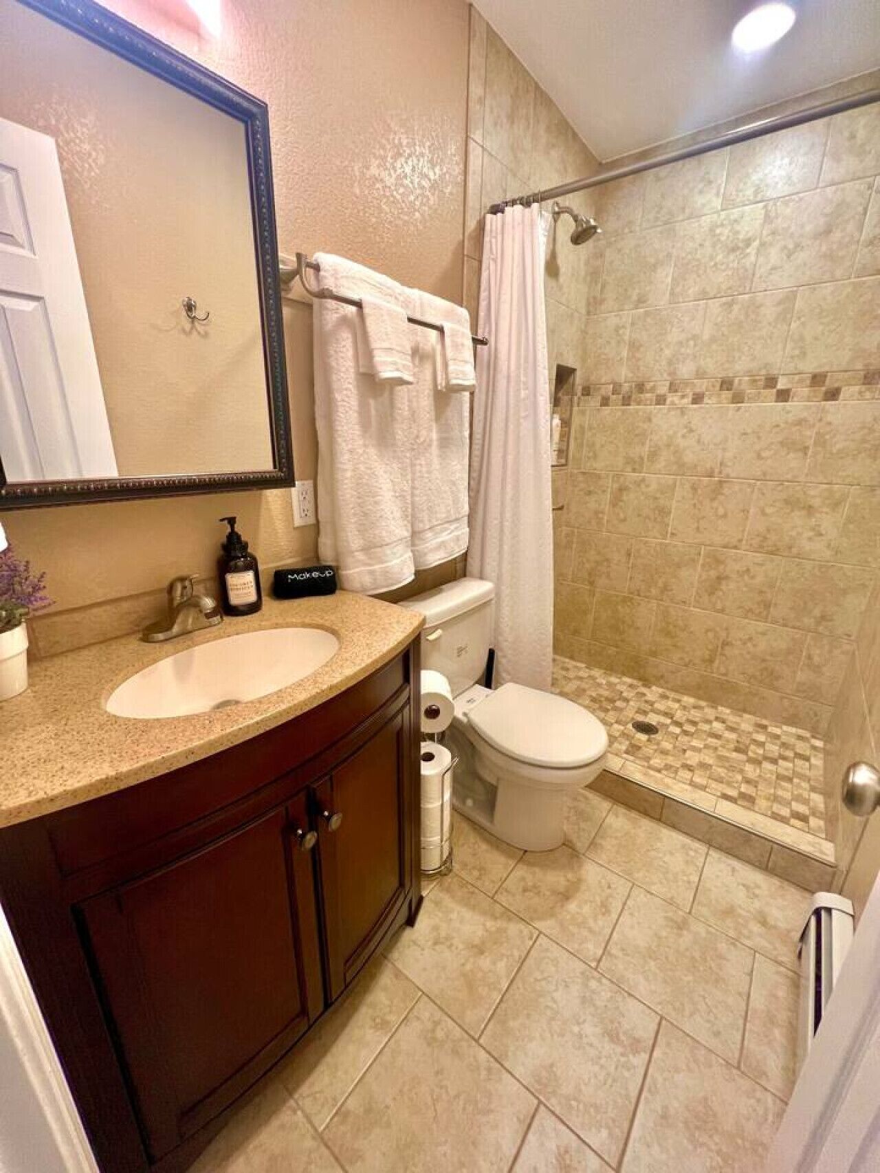 A bathroom with a sink, mirror, toilet, and shower.