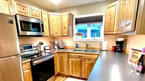 Une cuisine moderne avec des meubles en bois, des appareils électroménagers en acier inoxydable et un four encastré.