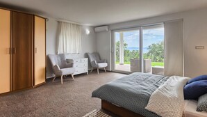 A bedroom with a bed, two chairs, a dresser, and a sliding glass door leading to an outdoor area. - Awesome home in Kostrena (Kostrena)