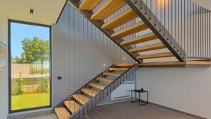 Un escalier moderne avec des marches en bois et des rampes en métal, menant à un deuxième étage.