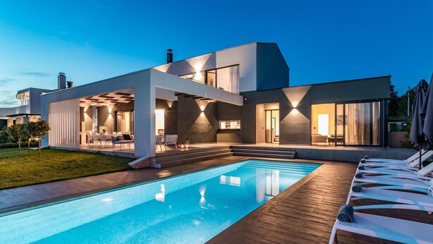 Une maison moderne dotée d’une piscine, d’un espace salon extérieur et d’une terrasse bien éclairée.