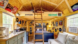A rustic cabin with a loft bedroom, a kitchen with a sink, and a living area with a couch.