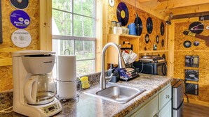 A kitchen with a coffee maker, sink, and wooden walls adorned with vinyl records.