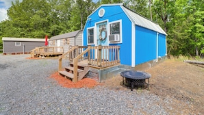 A blue building with a wooden staircase leading to a deck, surrounded by gravel and trees. - Higden Studio w/ Shared Patio, Yard Games, Grills! (Higden)