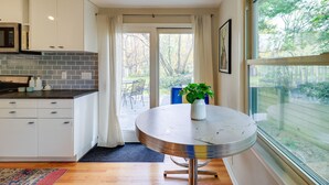 A modern kitchen with white cabinets, a gray backsplash, and a round table with a plant. - Ann Arbor Home w/ Deck, 2 Mi to Michigan Stadium! (Ann Arbor)