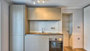 A modern kitchen with a built-in oven, a sink, and a stainless steel range hood. - Awesome home in Opatija (Opatija)
