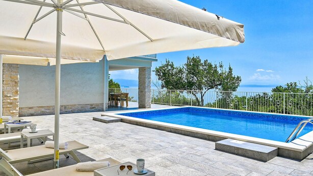 A poolside area with a clear view of the sea, a covered seating area, and a stone wall. - Awesome home in Opatija (Opatija)