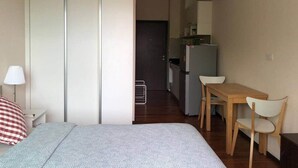 A compact room with a bed, a desk, a chair, a wardrobe, and a kitchenette. - Title by Villacarte (Tambon Rawai)