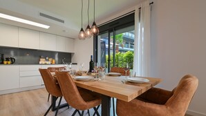 Een moderne keuken met witte kastjes, een houten eettafel en bruine stoelen.