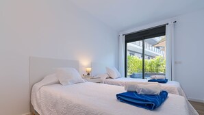 Een moderne hotelkamer met twee bedden, een groot raam en uitzicht op de omgeving.