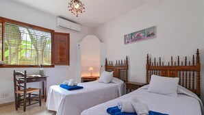 Une chambre d’hôtel avec deux lits, un bureau, une chaise et une fenêtre donnant sur un paysage verdoyant.