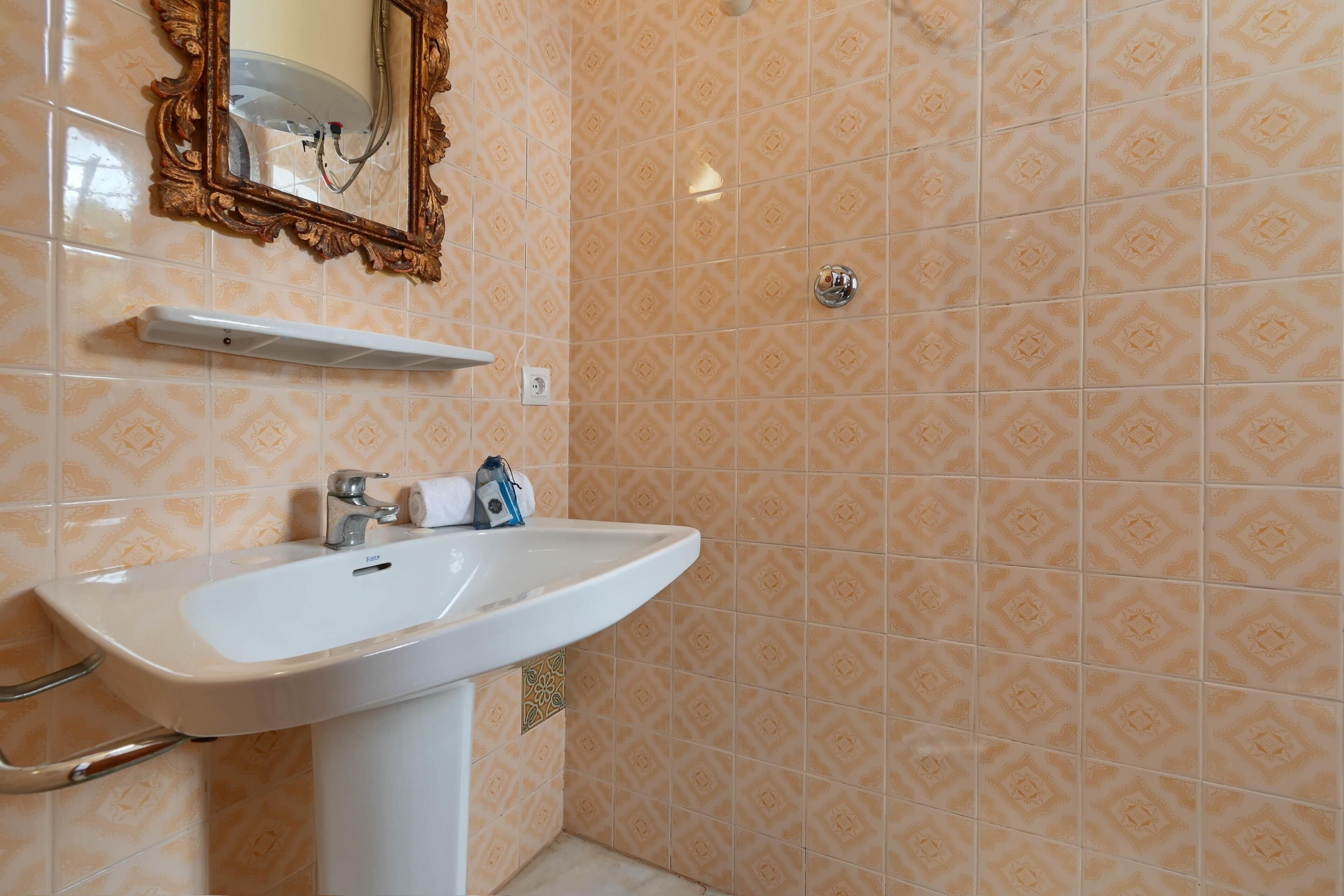 Une salle de bain avec un lavabo blanc, un miroir et des carreaux à motifs.
