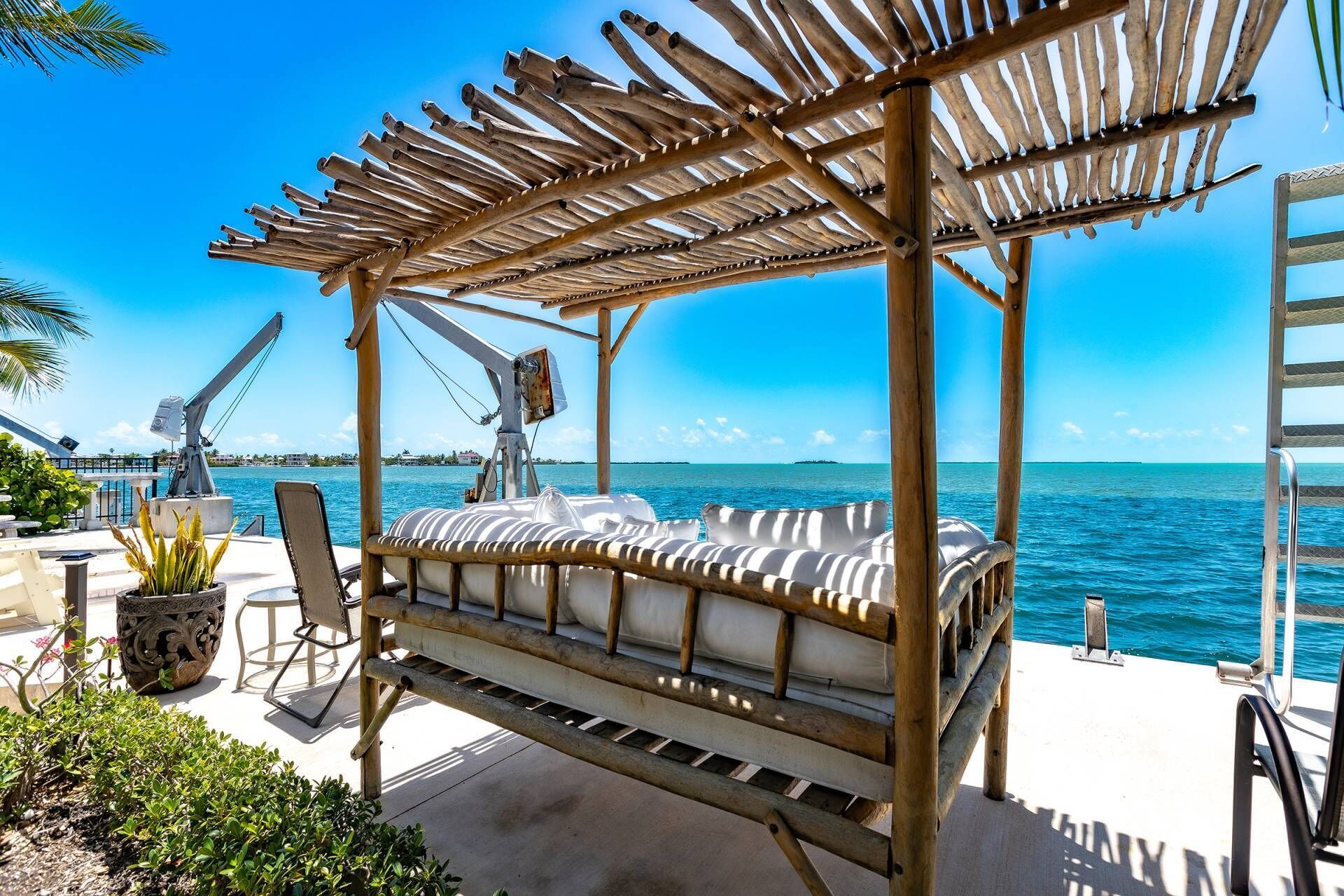 A wooden deck with a covered seating area overlooking a body of water.