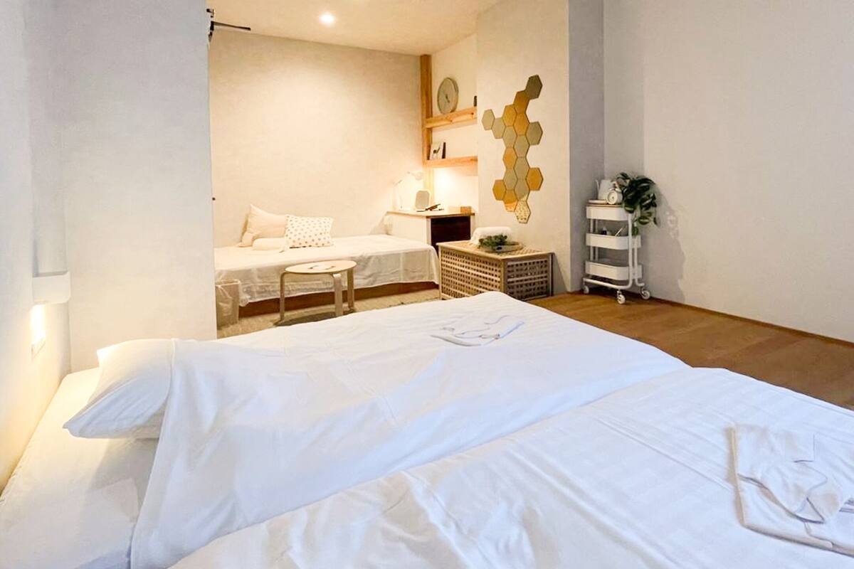 A hotel room with a large bed, a small desk, a nightstand, and a wall-mounted clock.