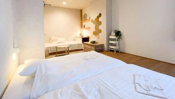 A hotel room with a large bed, a small desk, a nightstand, and a wall-mounted clock.