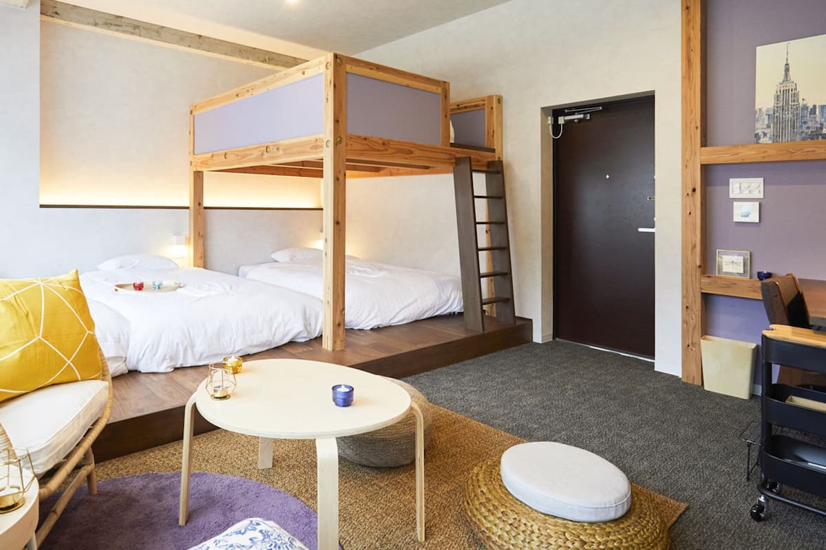 A room with bunk beds, a sofa, a small table, and a desk.