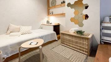 A neatly arranged bedroom with a bed, bedside table, lamp, and a wall-mounted clock.