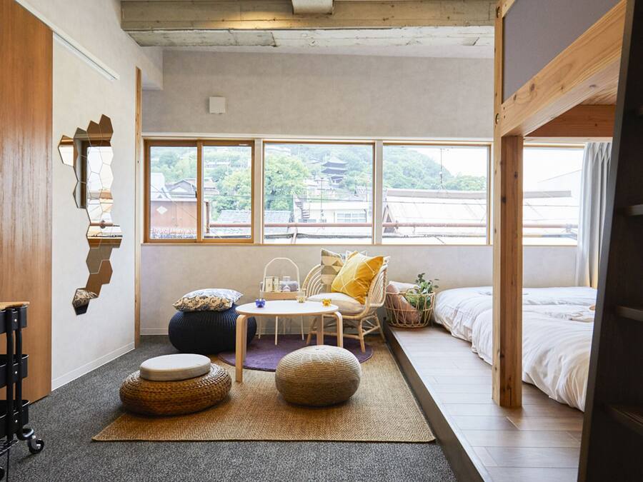 A compact, well-lit room with a bunk bed, a small table, and a chair.