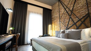 A hotel room with a large bed, a desk with a lamp, and a brick wall. - Rest & More by Dedeman Mersin Erdemli (Erdemli)