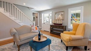 A living room with a staircase, a sofa, a chair, a wooden coffee table, and a decorative mirror. - Pet-Friendly Tilghman Island Coastal Retreat (Tilghman Island)