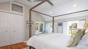 A bedroom with a large bed, a ceiling fan, white walls, and a window with shutters. - Pet-Friendly Tilghman Island Coastal Retreat (Tilghman Island)